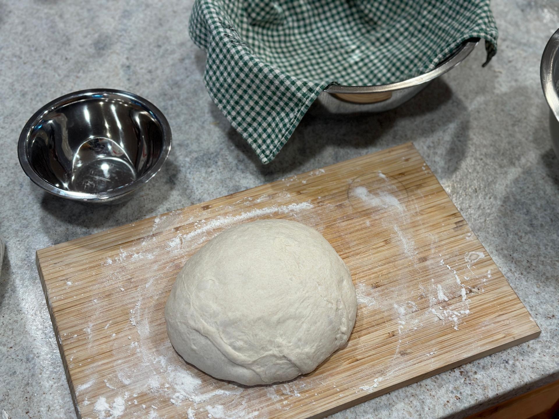 Woman kneading dough at table in kitchen, closeup